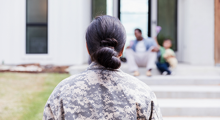 female veteran in front of a house and family